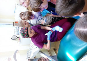 Pani stomatolog pokazuje dzieciom jak utrwala się założoną na zęba plombę